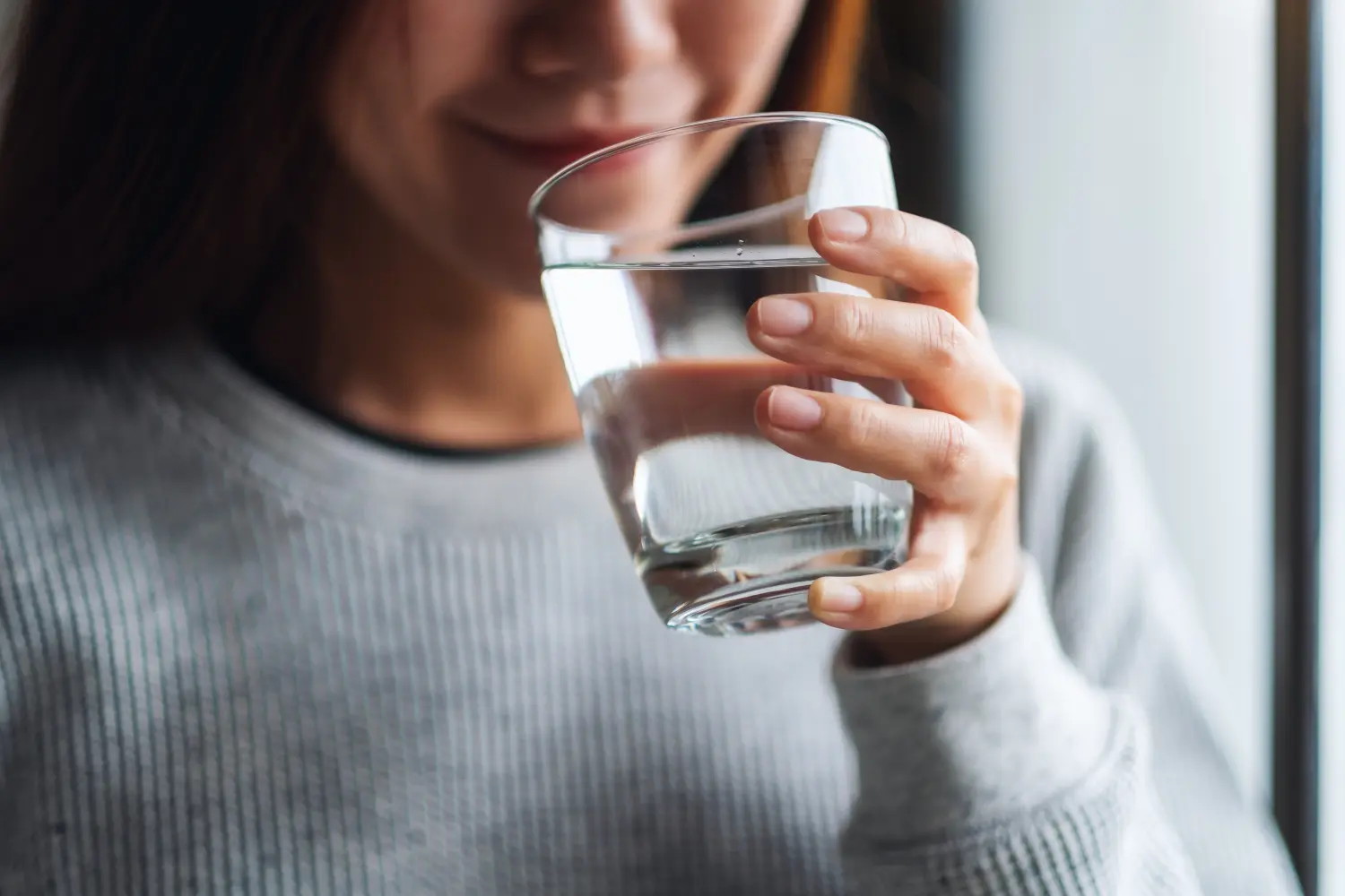Nahaufnahme einer schönen jungen Asiatin mit einem Glas Wasser